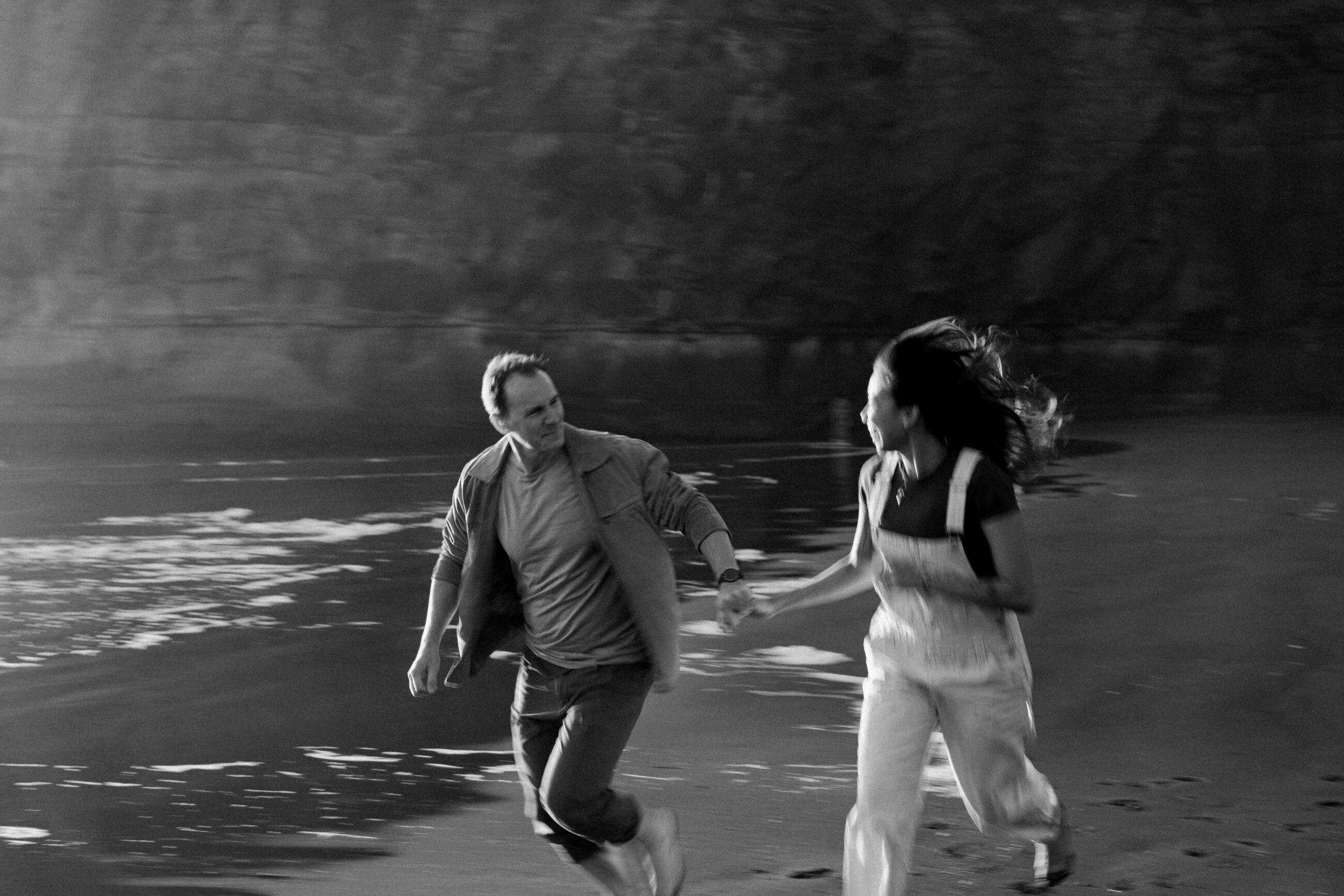 Couple running at sunset on Muriwai Beach in Auckland